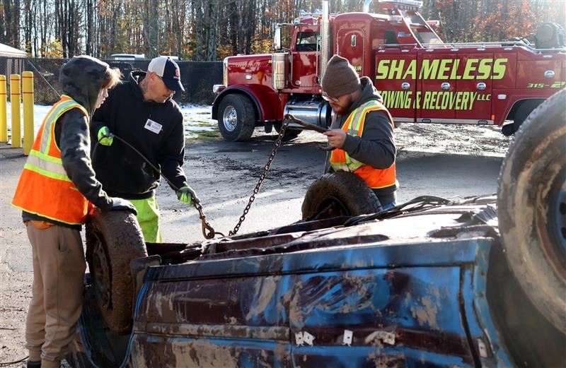  CTE students work on attaching chains to a car for a towing demonstration